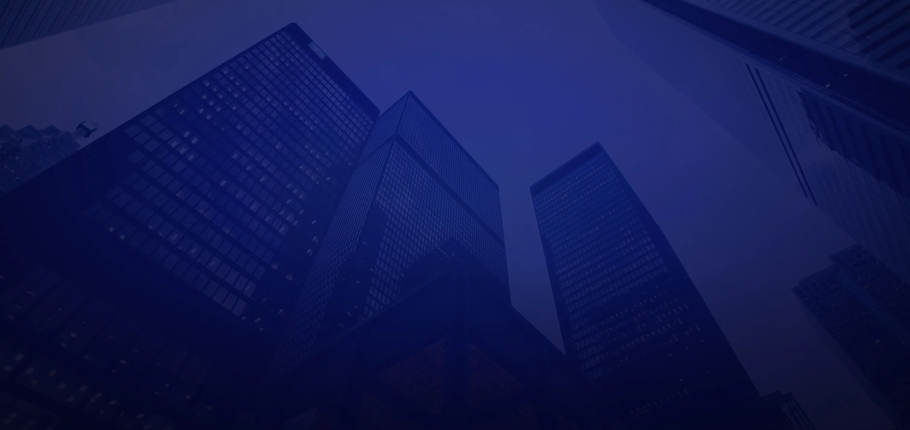 Low-angle view of modern glass skyscrapers against a dusky sky.